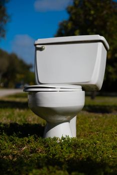 A white toilet set outdoors on grass in Miami, Florida, under a blue sky.